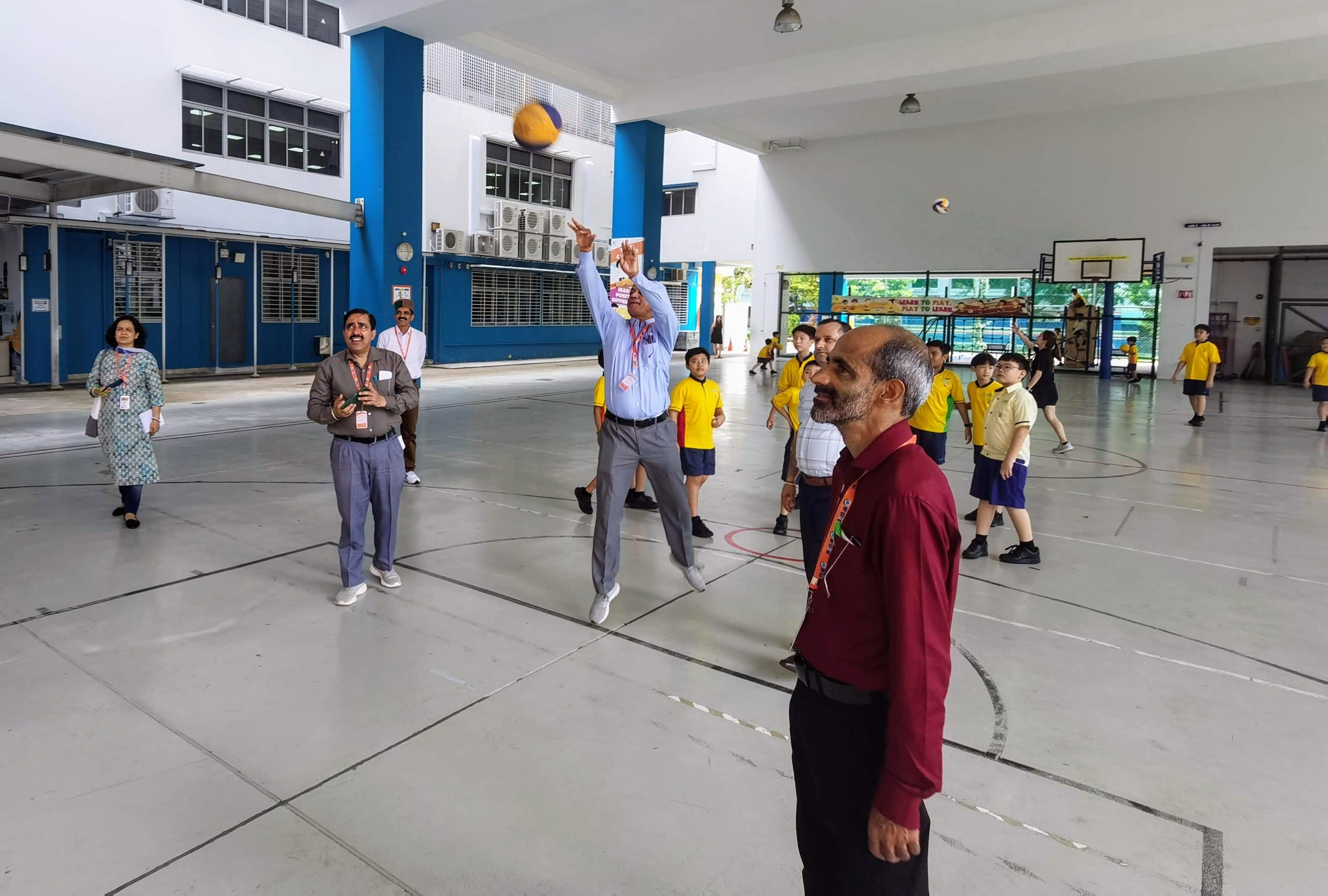Guests and students experiencing a PE lesson, playing basketball in the basketball court